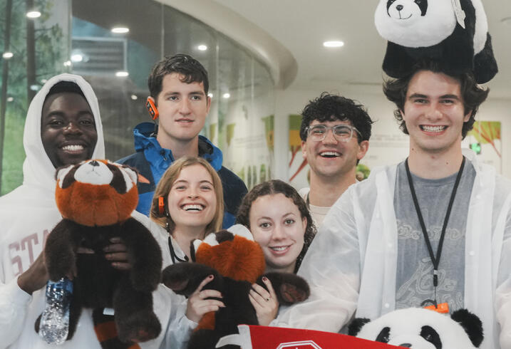 Students pose with stuffed pandas and a Stanford flag.