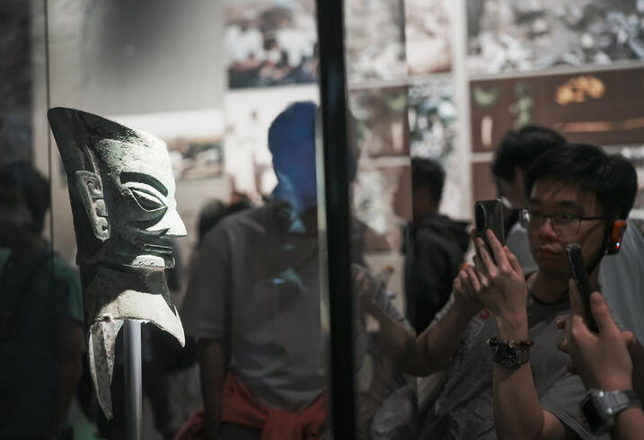 Students look at an ancient vase in a glass case.