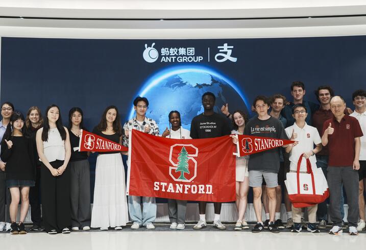 A group of students stand with a Stanford flag.