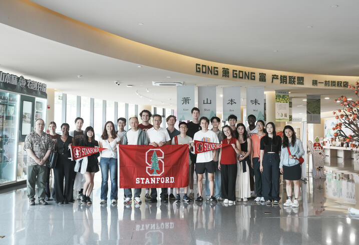 A group of students stand with a Stanford flag.