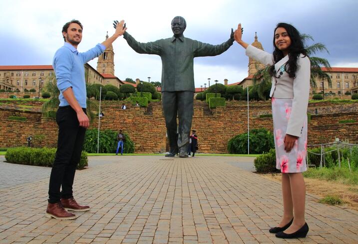 Eli MacKinnon and Janani Mohan with a statue of Nelson Mandela in South Africa.