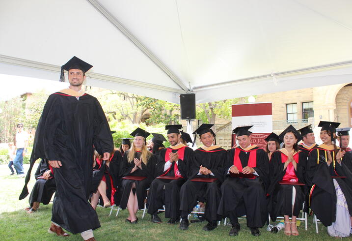 Graduates from the 2022 class of the Ford Dorsey Master's in International Policy walk up to accept their diplomas.