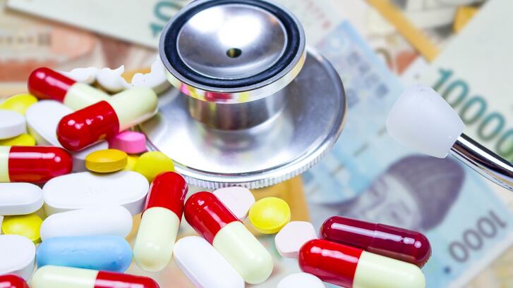Close-up on coloured medication capsules and a stethoscope on the background of Korean won bills.