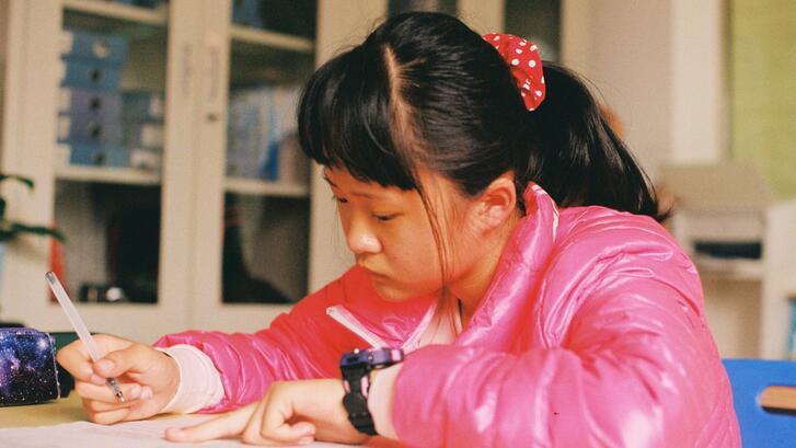A girl in China sits at a classroom desk taking a test. 