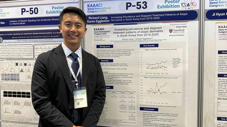 Richard Liang standing next to a poster presenting his research at a conference. 