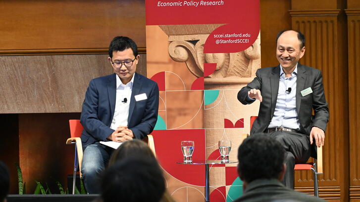 Yiqing Xu and Hongbin Li sit on a stage during a SCCEI event.