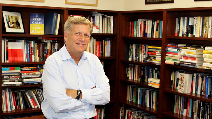 Professor Michael McFaul, director of the Freeman Spogli Institute, stands in front of his desk.