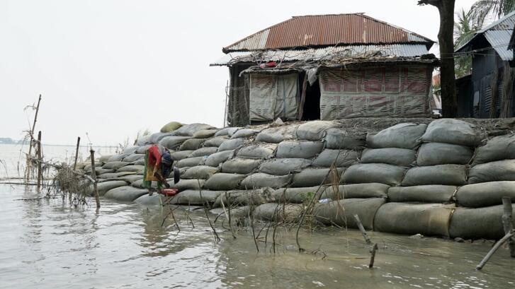A woman stands on sandbags stacked to protect against flooding in Barisal, Bangladesh.