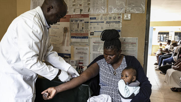 In Keny, a doctor administers to an AIDs patient holding her child.