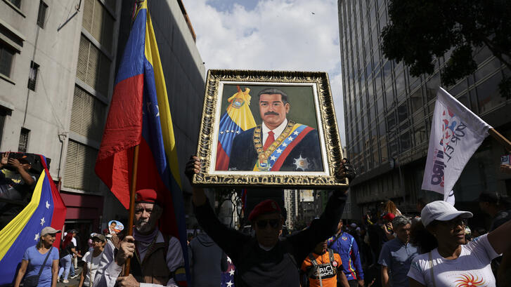 man holds a portrait of nicolas maduro during a march