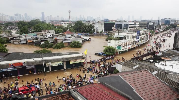People walk through the flooded streets at Kampung Pulo on January 18, 2014 in Jakarta, Indonesia.