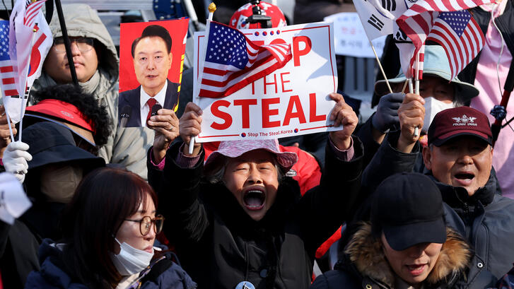 Supporters of impeached South Korean President Yoon Suk Yeol gather on April 4, 2025 in Seoul, South Korea, with a foucs on a man holding a sign reading "Stop the Steal" and an American flag.