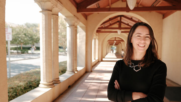 Stanford's Maria Polyakova stands amid the university's sandstone columns.