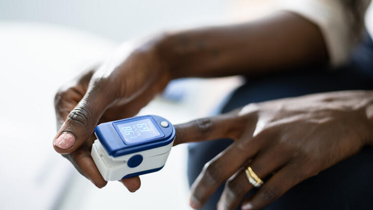 Photo of a dark-skinned woman using a pulse oximeter