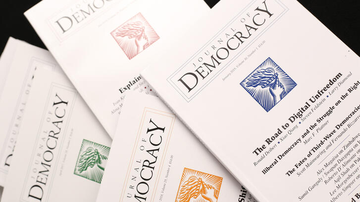 Spread of issues of the Journal of Democracy on black background