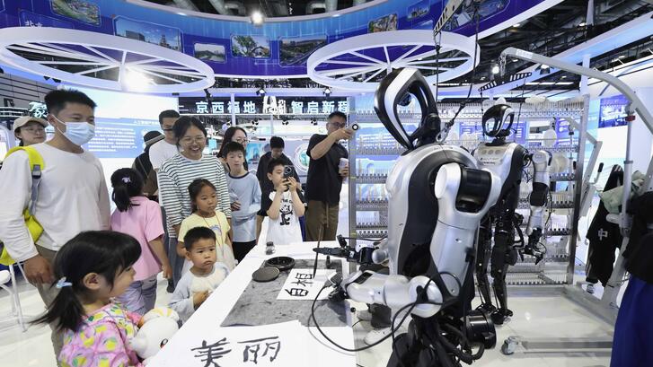 Visitors watch humanoid robots writing calligraphy during the 28th China Beijing International High-Tech Expo at China National Convention Center on May 9, 2026.