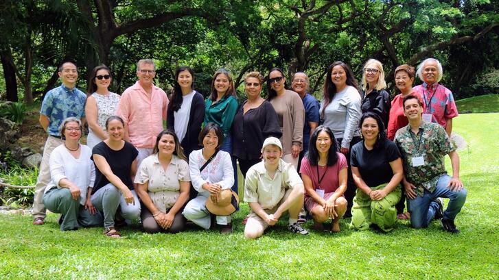 group of educators posing in front of a lush green canopy