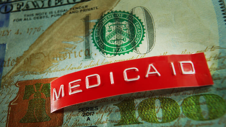 Photo illustration of Medicaid label on top of a U.S. dollar
