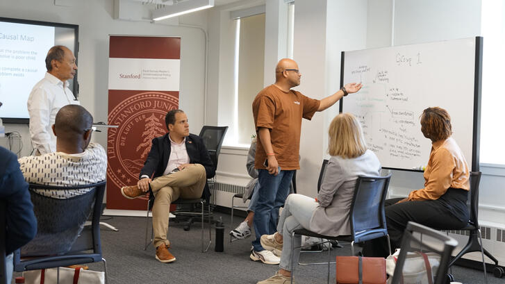 Francis Fukuyama looks on as a group of fellows works through a case study.