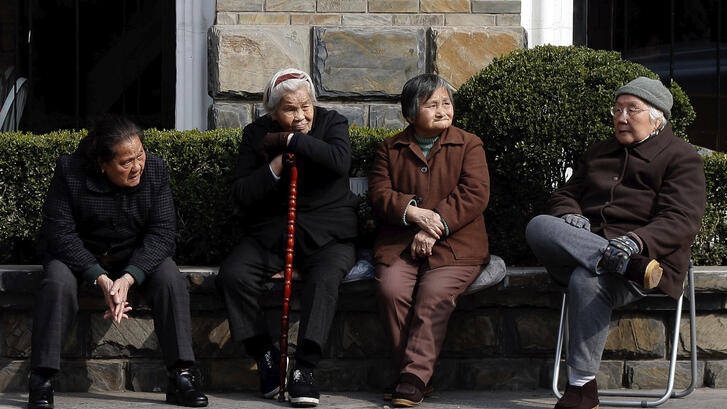 Four elderly Chinese people sitting outdoors. 