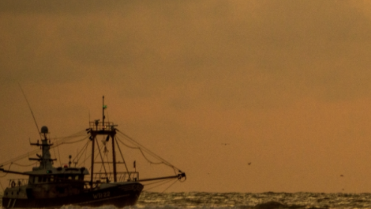 A fishing boat at sea under a hazy sky