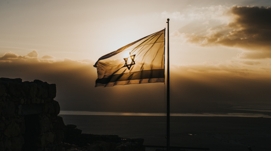 The flag of Israel flies against a sunlit sky
