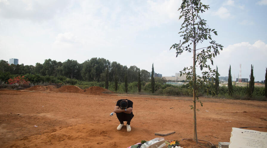 A mourner kneels at the funeral of May Naim in Israel following the massacre at music festival