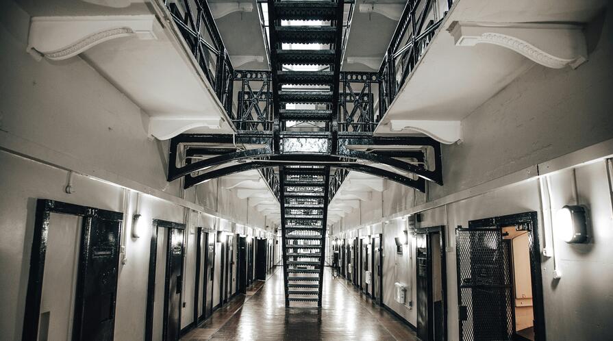 Prison corridor with jail cells on either side.