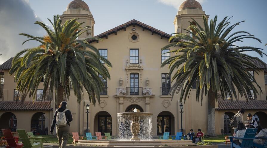 a fountain and two palm trees in front of a building