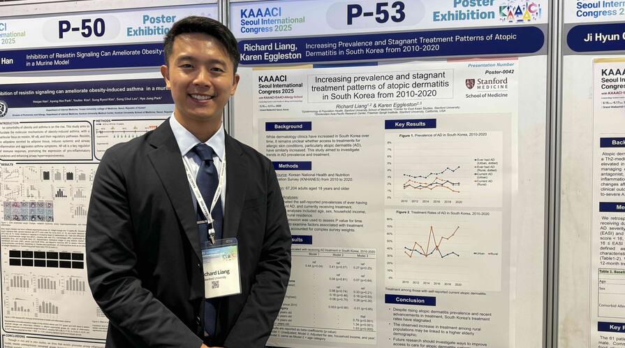 Richard Liang standing next to a poster presenting his research at a conference. 