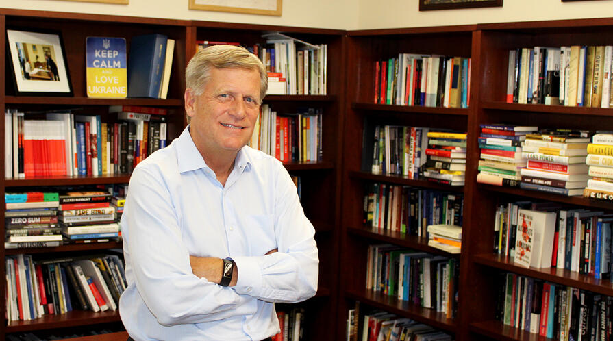 Professor Michael McFaul, director of the Freeman Spogli Institute, stands in front of his desk.