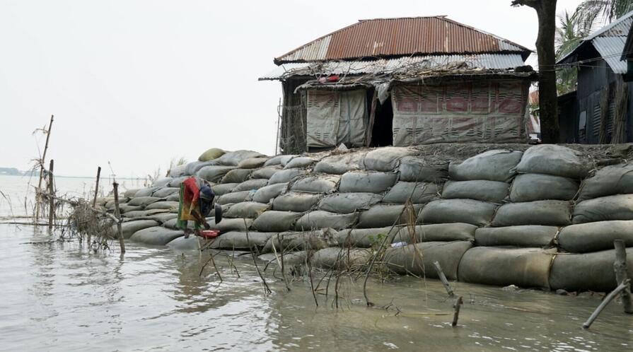 A woman stands on sandbags stacked to protect against flooding in Barisal, Bangladesh.