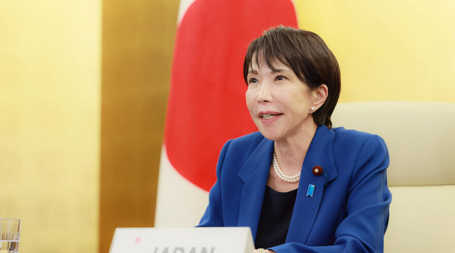 Japanese Prime Minister Sanae Takaichi delivers remarks while seated in front of the Japanese flag.