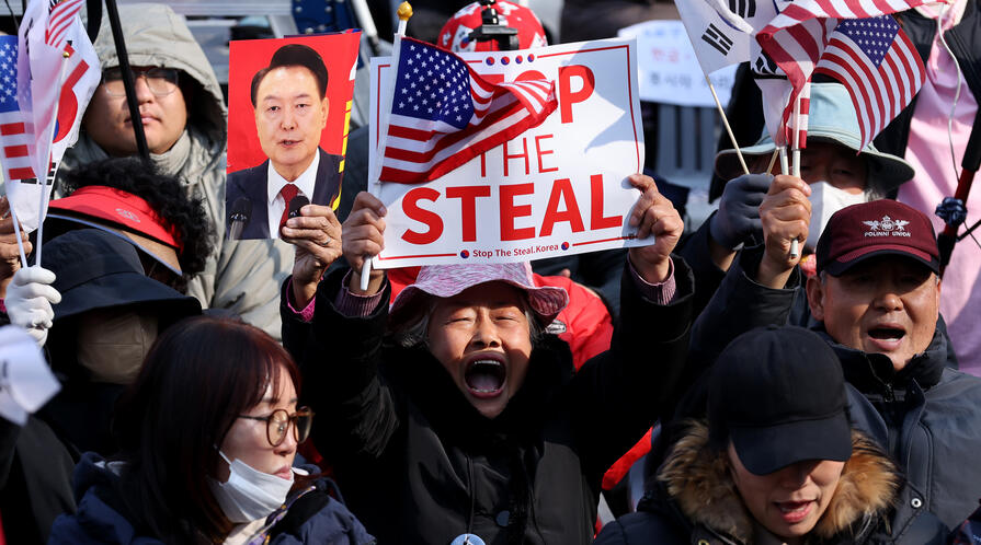Supporters of impeached South Korean President Yoon Suk Yeol gather on April 4, 2025 in Seoul, South Korea, with a foucs on a man holding a sign reading "Stop the Steal" and an American flag.