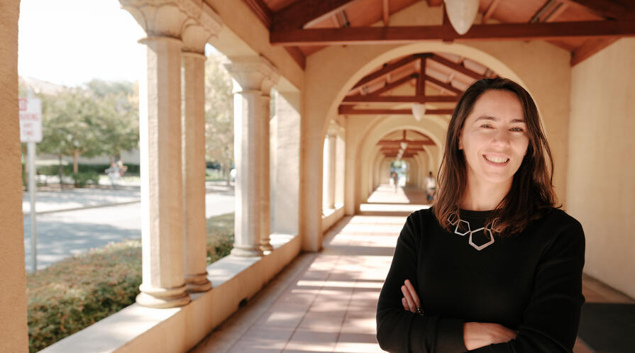 Stanford's Maria Polyakova stands amid the university's sandstone columns.