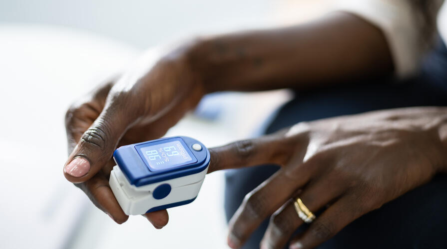 Photo of a dark-skinned woman using a pulse oximeter