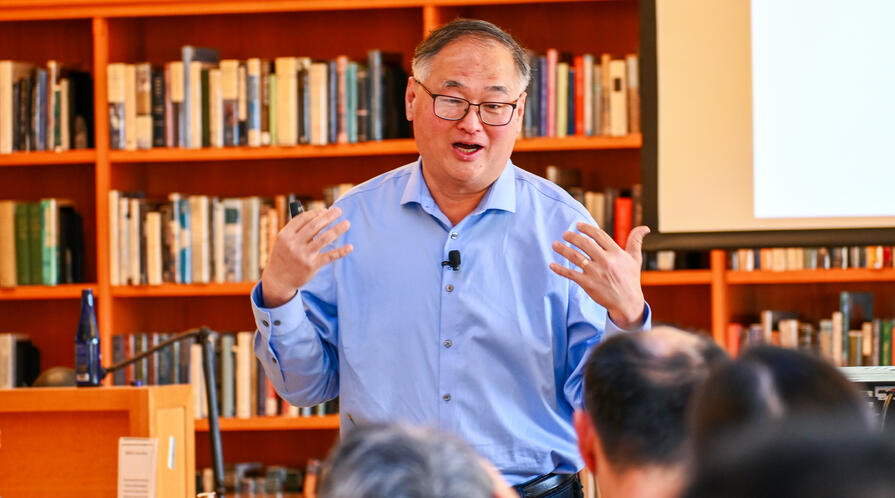 Chang-Tai Hsieh speaks during a lecture in a library. 