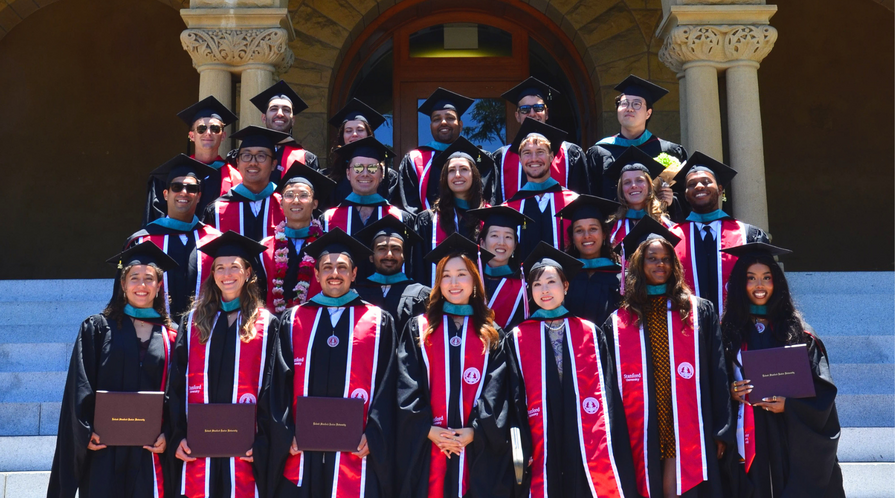 Graduates of the Ford Dorsey Master's in International Policy Class of 2026 pose on the steps of Encina Hall at Stanford University in their caps and gowns and diplomas.