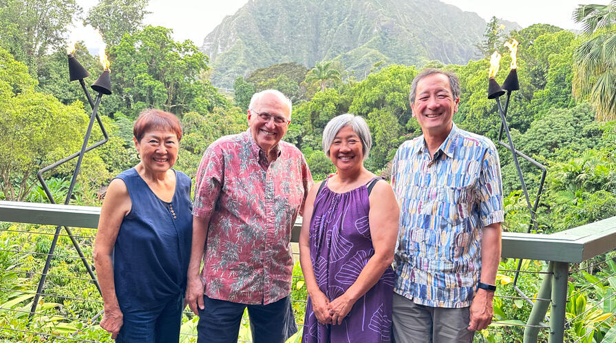 four people standing in Hawaiin shirts and dresses