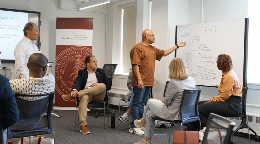 Francis Fukuyama looks on as a group of fellows works through a case study.