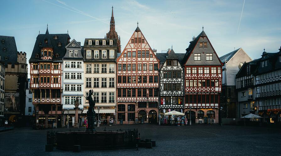 Row of half-timbered buildings on Frankfurt’s Römerberg square, with a Justitia fountain statue in the foreground.