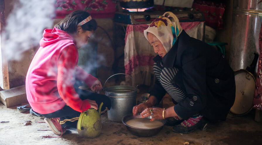 A mother and child preparing food inside a yurt in rural China. 